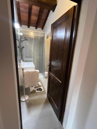 a bathroom with a wooden door and a sink at La finestra sulla torre in Castiglion Fiorentino