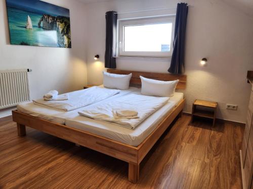 a bedroom with a bed with white sheets and a window at Gästehaus Parkblick in Rust