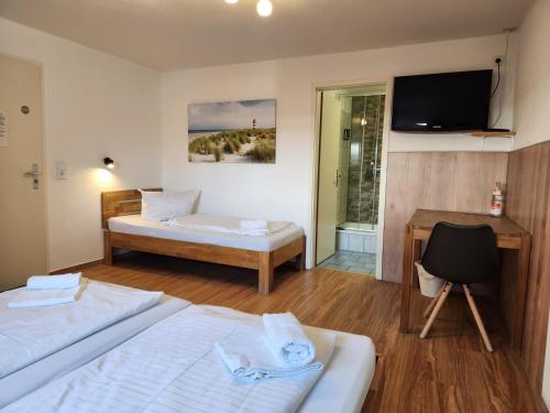 a room with two beds and a desk and a television at Gästehaus Parkblick in Rust