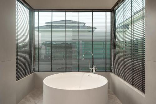 a bathroom with a tub in front of a large window at Sun Diego Resort Pool Villa in Jomtien Beach