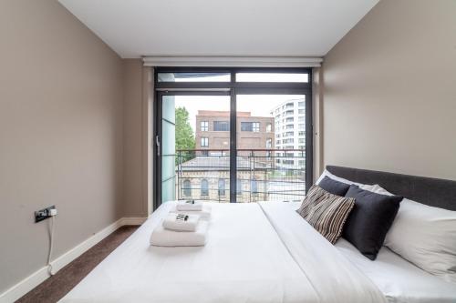 a bedroom with a large white bed with a large window at Magnificent 2 BR flat, Caledonian Road in London