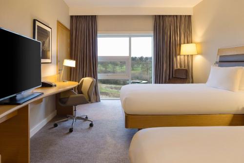 a hotel room with a bed and a desk with a computer at Hilton at St George's Park in Burton upon Trent
