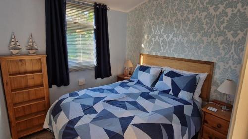 a bedroom with a blue and white bed and a window at The Lookout - Chalet 32 in Carmarthen