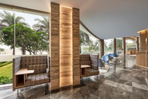 a lobby with chairs and tables and large windows at Sheraton Hai Phong in Hai Phong