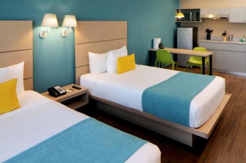 a hotel room with two beds and a kitchen at City Express Suites by Marriott Tijuana Rio in Tijuana