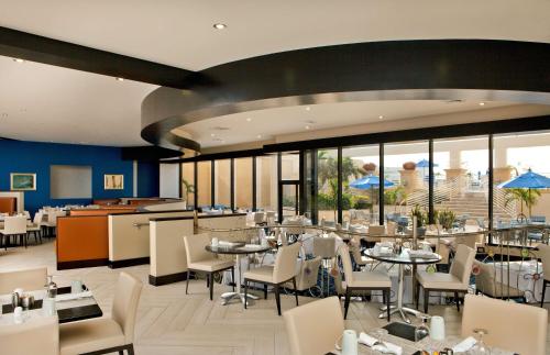 uma sala de jantar com mesas, cadeiras e janelas em Hilton Miami Downtown em Miami