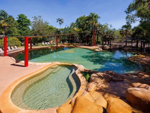 a large swimming pool in a park with rocks at Cooinda Lodge Kakadu in Jabiru