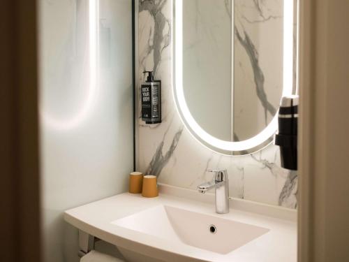 La salle de bains blanche est pourvue d'un lavabo et d'un miroir. dans l'établissement IBIS Caen Centre, à Caen