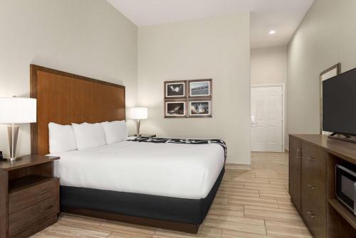 a hotel room with a bed and a flat screen tv at La Quinta by Wyndham Brownsville North in Brownsville