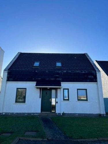 une maison blanche avec un toit noir dans l'établissement Saint Andrews Rosslare Strand County Wexford, à Rosslare