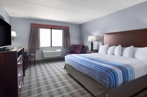 a hotel room with a bed and a television at AmericInn by Wyndham Stuart in Stuart