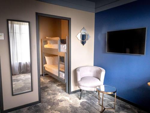 a room with a chair and a mirror and a tv at Hôtel Mercure Rochefort La Corderie Royale in Rochefort