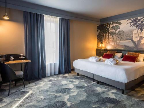 a hotel room with a large bed and a desk at Hôtel Mercure Rochefort La Corderie Royale in Rochefort