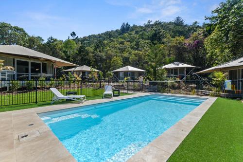 a swimming pool with two chairs and a house at DeluxeQueenSafariTent1 in Nelly Bay
