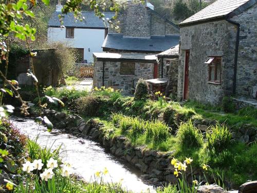 an old stone house with a garden with flowers at Homer Barn in Tavistock