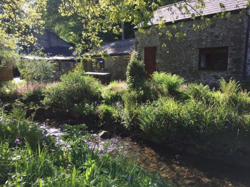 a garden with a stone building and plants at Homer Barn in Tavistock