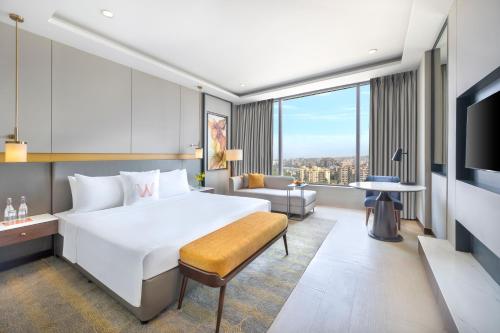 um quarto de hotel com uma grande cama branca e um sofá em Welcomhotel by ITC Hotels, Dwarka, New Delhi em Nova Deli