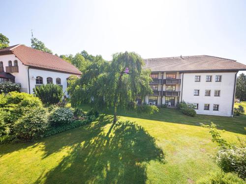 an apartment building with a tree in front of a yard at Hotel am Badepark Waldkirchen in Waldkirchen