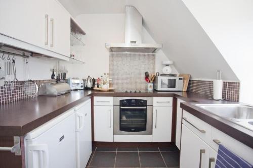 eine Küche mit weißen Schränken und einem Herd mit Backofen in der Unterkunft Bournecoast: Spacious apartment with WIFI - FM9589 in Bournemouth