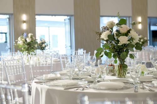 a white table with glasses and a vase of flowers at Hilton Los Angeles-Culver City, CA in Los Angeles