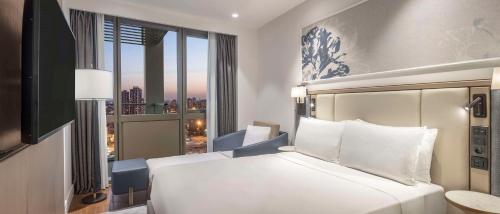 a bedroom with a white bed and a large window at Hilton Mall Of Istanbul in Istanbul
