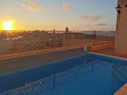 uma piscina com o pôr-do-sol ao fundo em Bed and breakfast "Selena" with swim pool em Nadur