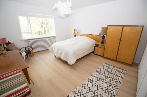 a bedroom with a white bed and a wooden cabinet at Sunny Reykjavik Family Apartment in Reykjavík