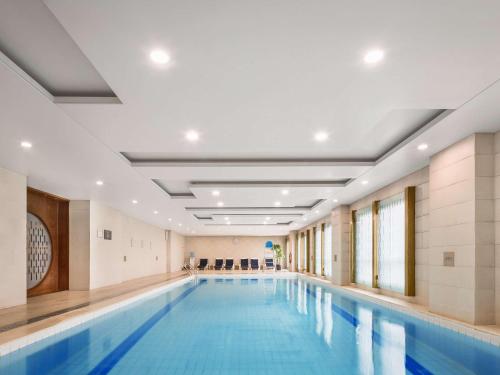a large swimming pool in a building with a swimming poolvisorvisor at Swissôtel Shenyang in Shenyang