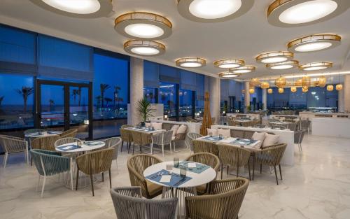 ein Restaurant mit Tischen, Stühlen und Fenstern in der Unterkunft Hilton Skanes Monastir Beach Resort in Monastir