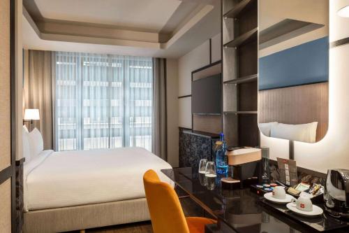 a hotel room with a bed and a desk and a bed and a window at Athens Key Hotel, Trademark Collection by Wyndham in Athens