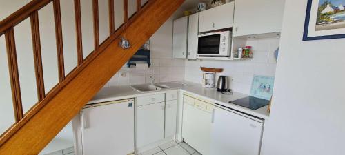 une petite cuisine avec des placards blancs et un escalier dans l'établissement Ref 094 - A louer appartement pour six vue mer proche plage du Fogeo, à Arzon
