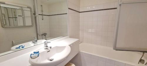 une salle de bain blanche avec un lavabo et une baignoire dans l'établissement Ref 094 - A louer appartement pour six vue mer proche plage du Fogeo, à Arzon