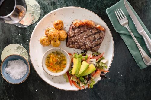 a plate of food with meat and vegetables and a salad at Santa Marta Marriott Resort Playa Dormida in Santa Marta