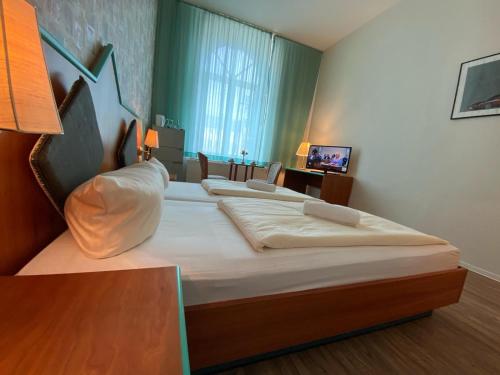 a bedroom with two beds and a television in it at Rathaushotel in Eibenstock