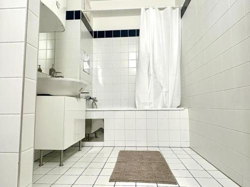 ein weißes Bad mit einem Waschbecken und einer Dusche in der Unterkunft Chic Apartment - Quiet Area - Next to Hospital in Wien