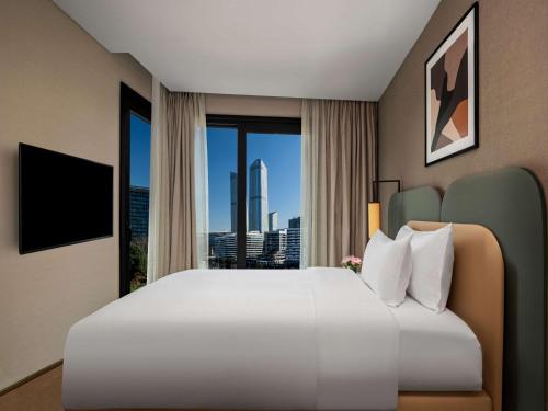 a hotel room with a large bed and a large window at Mövenpick Living Istanbul Saklivadi in Istanbul