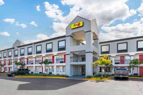 an exterior view of a hotel with a ford dealership at Super 8 by Wyndham Orlando Near Florida Mall in Orlando