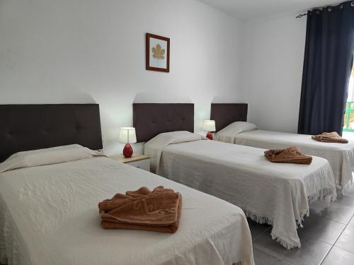 a hotel room with three beds with towels on them at RealRent Costa Teguise Beach in Costa Teguise