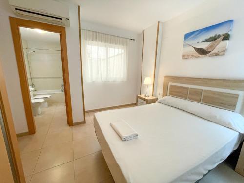 1 dormitorio con cama blanca y baño en Apartamentos Alcoceber Centro 3000, en Alcossebre