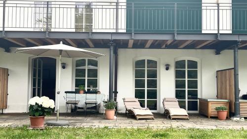 eine Terrasse mit einem Tisch, Stühlen und einem Sonnenschirm in der Unterkunft Gutshof Ferienwohnung in Seenähe in Dießen am Ammersee