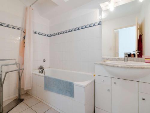 La salle de bains blanche est pourvue d'un lavabo et d'une baignoire. dans l'établissement Appartement T4 Rez-de-Jardin Proche Plage, Terrasse, Parking, 3 Chambres, Résidence Sécurisée - FR-1-409-224, à Narbonne