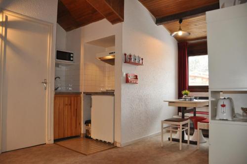 een keuken met een tafel, een koelkast en een aanrecht bij Olympe - 124 - Studio coquet - 3 pers in Les Deux Alpes