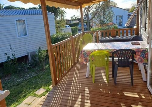 a patio with a table and chairs on a deck at Mobil-home (Clim, Tv, Lv)- Camping Lac des Rêves 4* - 009 in Lattes