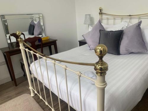 1 dormitorio con cama con sábanas blancas y almohadas moradas en Bayview, Dunmore East, County Waterford - Sleeps 12 persons en Dunmore East