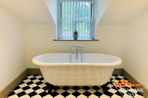 a bath tub in a bathroom with a checkered floor at 2Fountains Cottage - Stylish Cottage Hadrains Wall in Greenhead