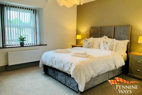 a bedroom with a large bed with white sheets and pillows at 2Fountains Cottage - Hadrian's Wall in Greenhead
