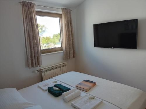 a room with a bed with a television on the wall at APARTMANI PETRA in Vir