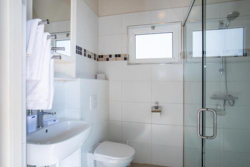 a white bathroom with a sink and a toilet at Tropical villa Curoyal near the beach in Jan Thiel