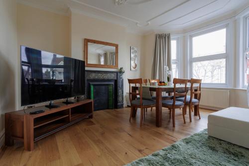 a living room with a television and a table with chairs at Luxury Apartment in Kensal Rise in London