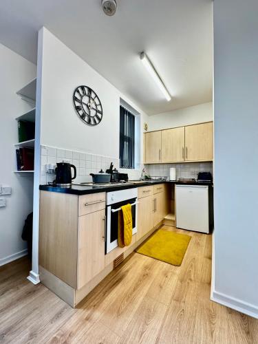 una cucina con armadi in legno e un orologio sul muro di Rooms Near Me - Apartment 4, Smart Tv, Free Parking a Halesowen